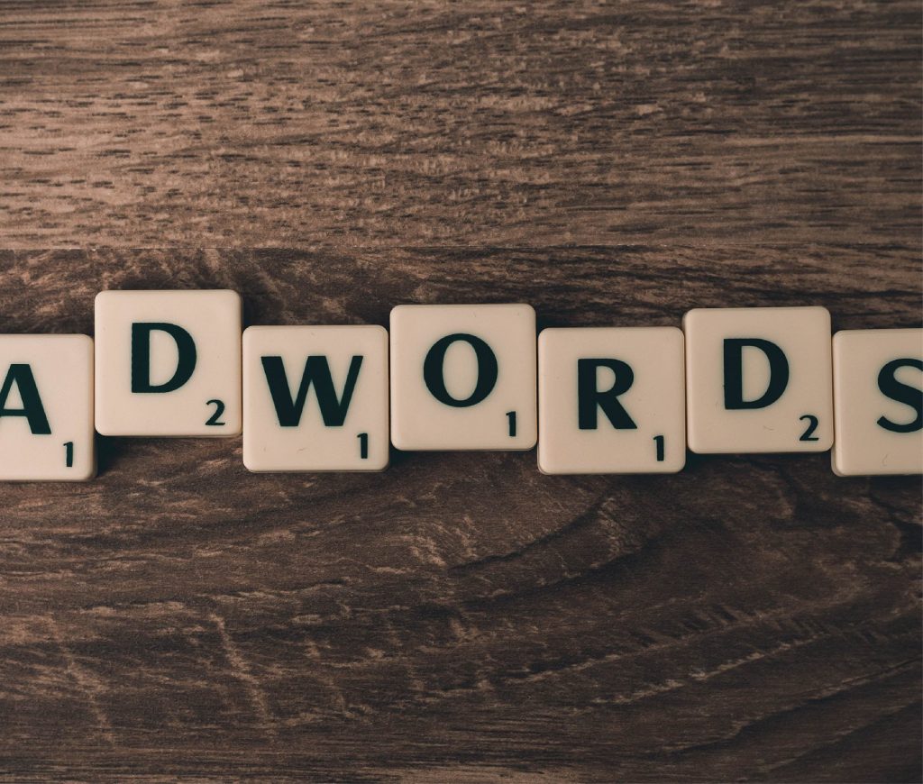 Pay-Per-Click - AdWords spelt using Scrabble tiles on dark brown wooden surface